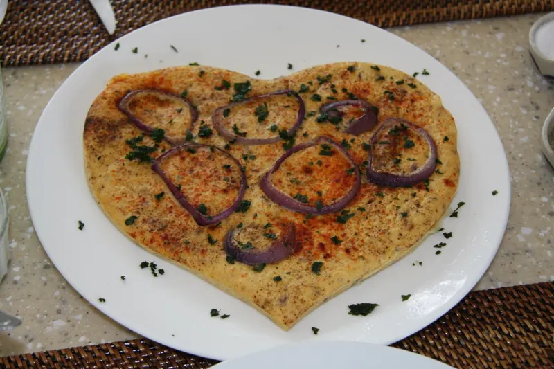 A heart-shaped flatbread topped with red onion