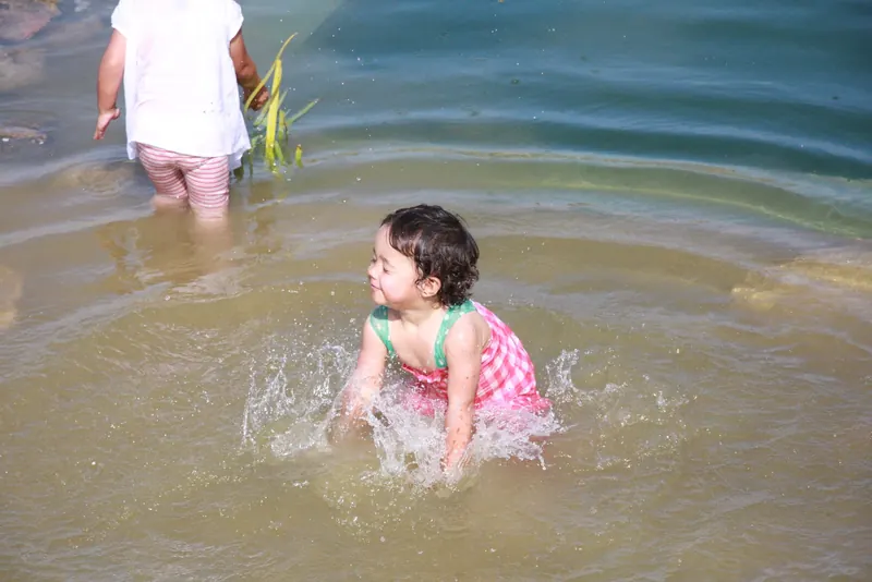 A small child splashing in the clear, shallow water
