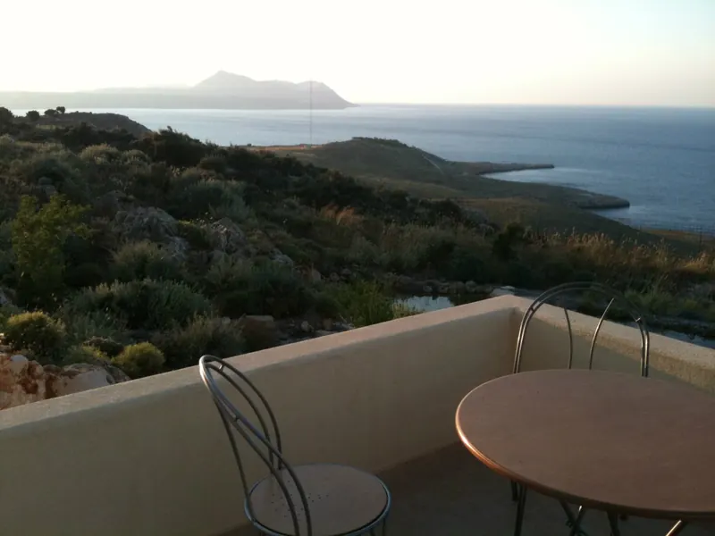 A terrace table and chairs at sunset, looking over the coast to the sea