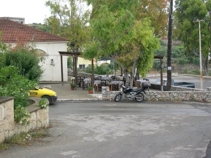 The village taverna with tables under trees beside the square